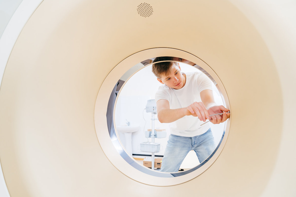 engineer with screwdriver assembles medical equipment after repair, installation, maintenance. CT scanner.