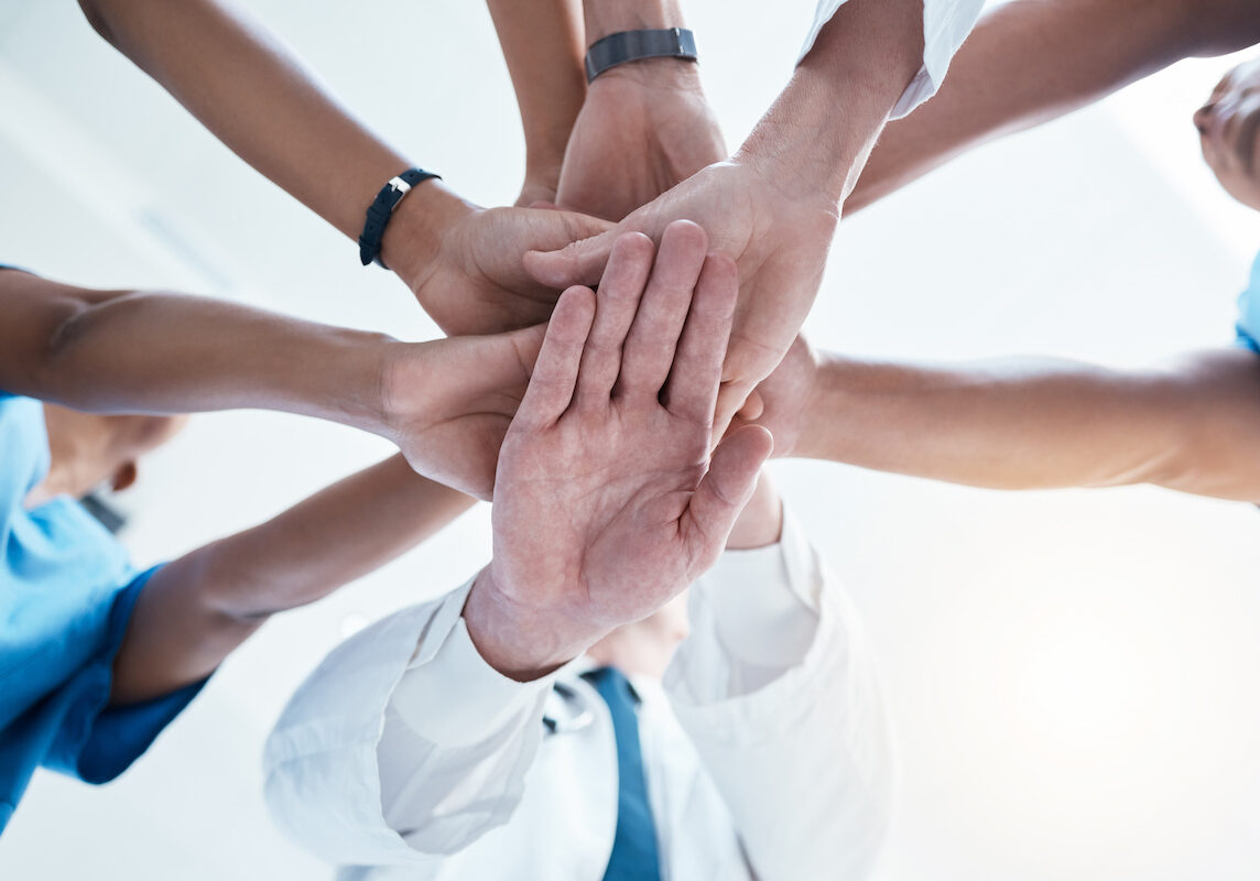 Below, group and hands stack for medical, staff and teamwork in hospital for motivation. Team, doctor and nurse with hand for collaboration, healthcare and help in community at job together in clinic.